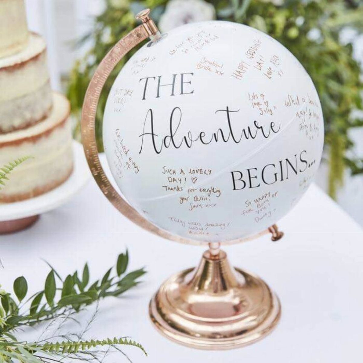White globe with gold stand signed by guests with handwritten messages and text.