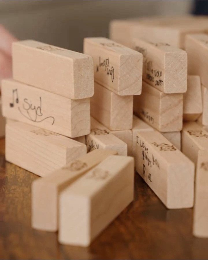 Wooden Jenga blocks with handwritten guest messages piled on a brown table.
