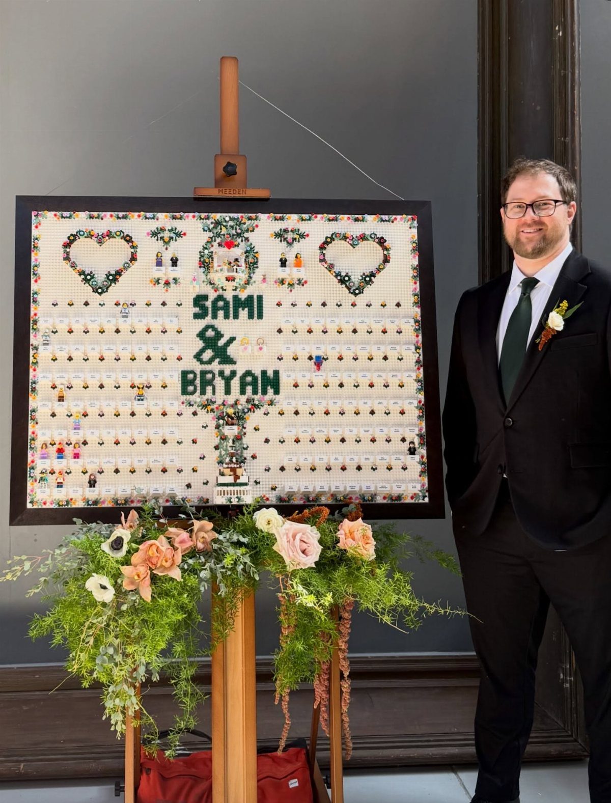 Lego guest book on an easel with names and hearts, next to a man.