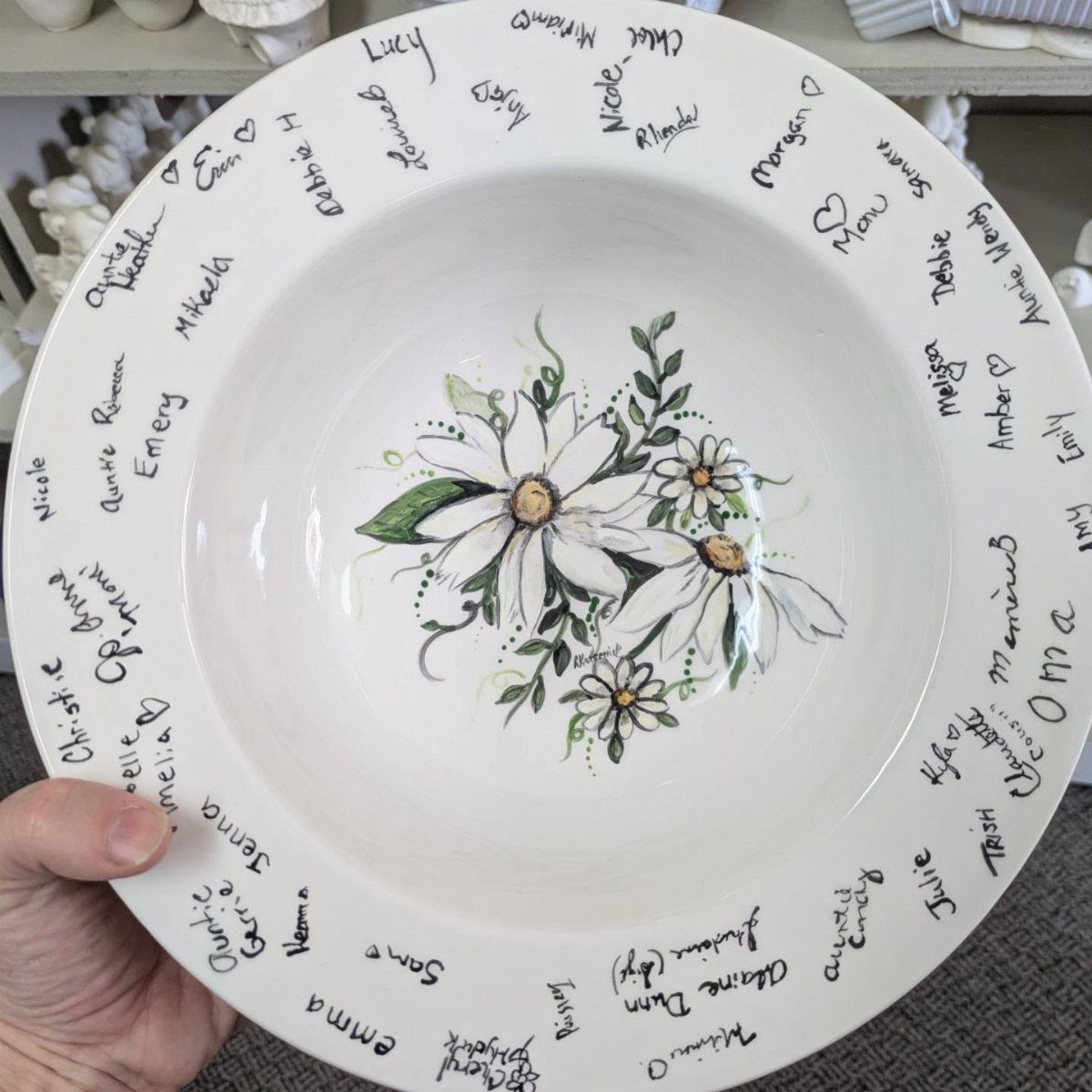 White ceramic bowl with floral center and guest names written on the rim