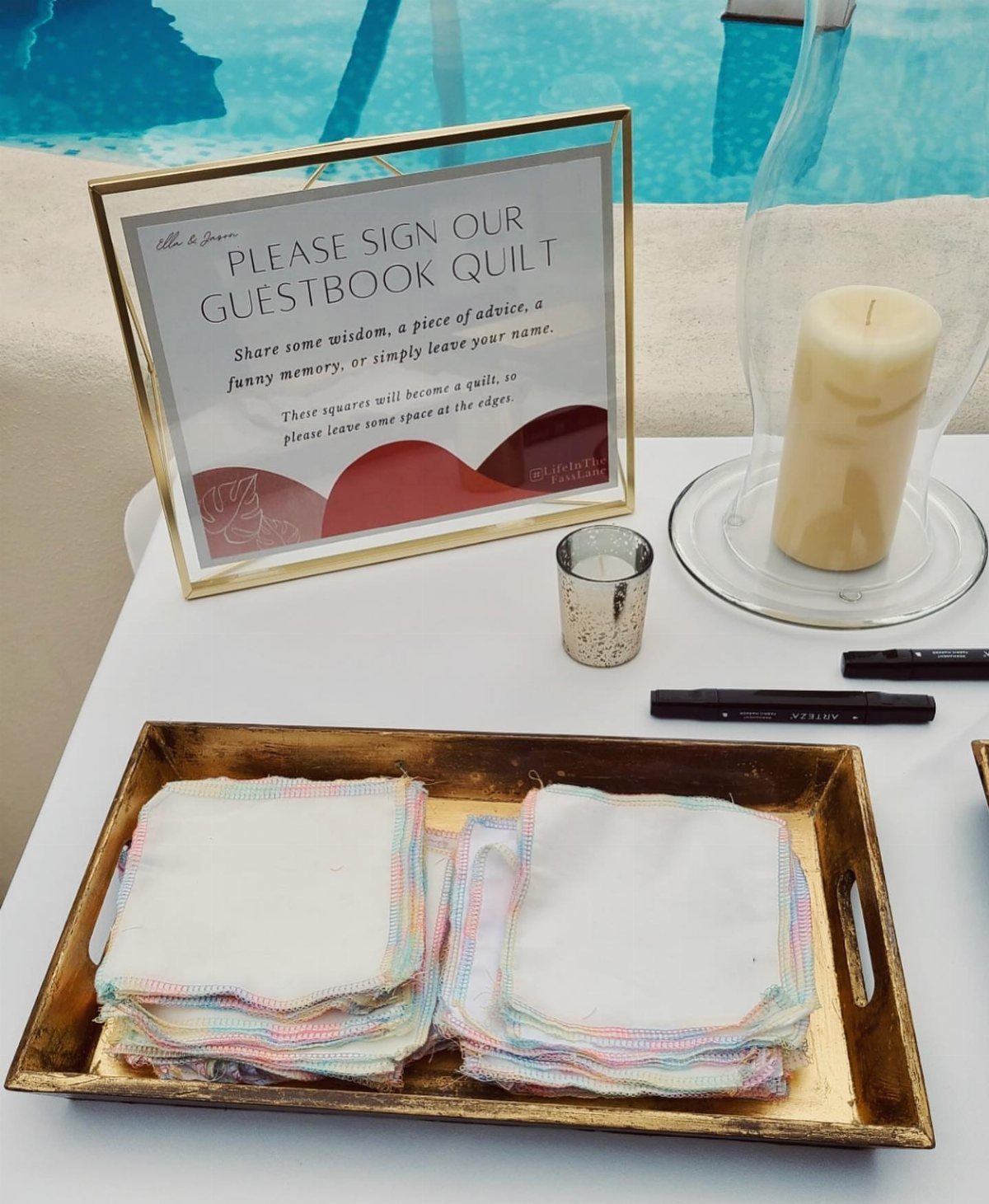 Fabric squares on a gold tray next to a guestbook quilt sign.
