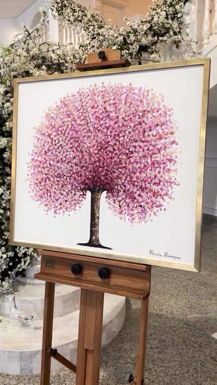 Framed painting of a pink tree on a wooden easel with floral background