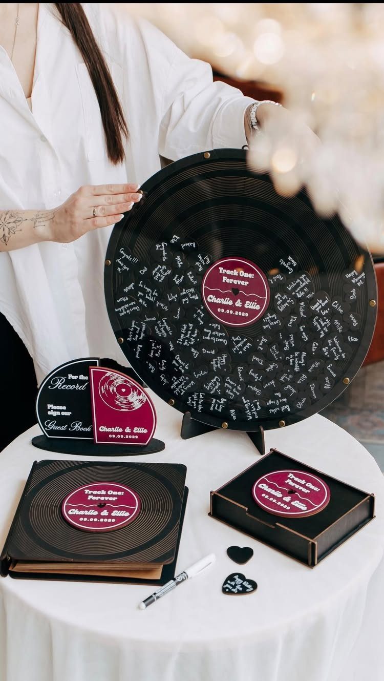Signed black vinyl record on a stand with matching wedding guest book accessories.