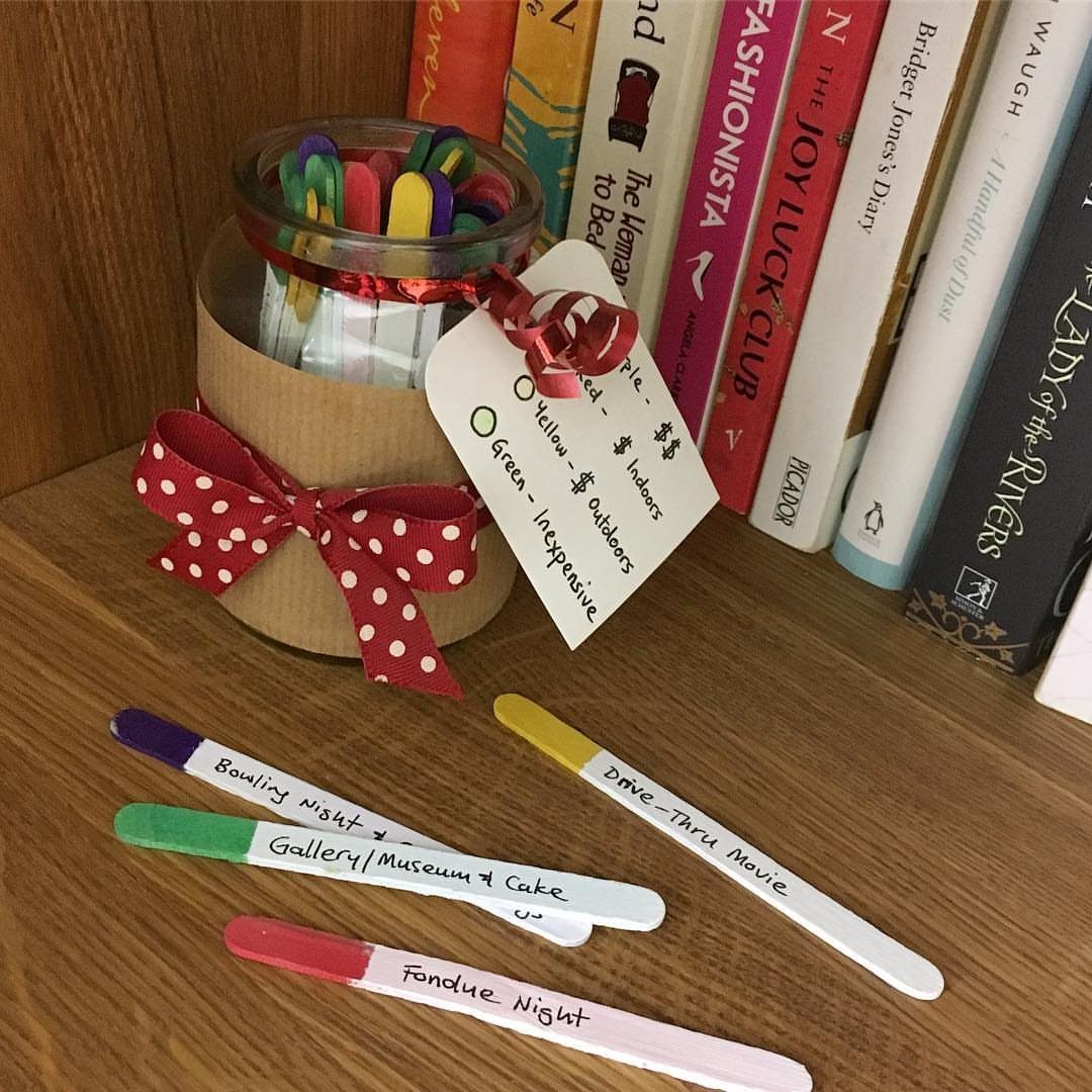 Glass jar with colorful popsicle sticks and handwritten date night ideas on a shelf