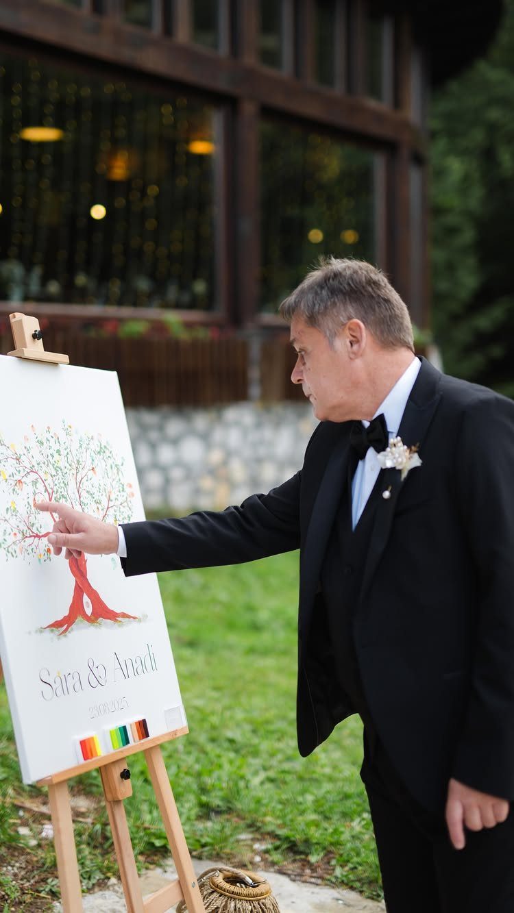 Man in tuxedo adding a fingerprint leaf to a fingerprint tree guest book canvas.