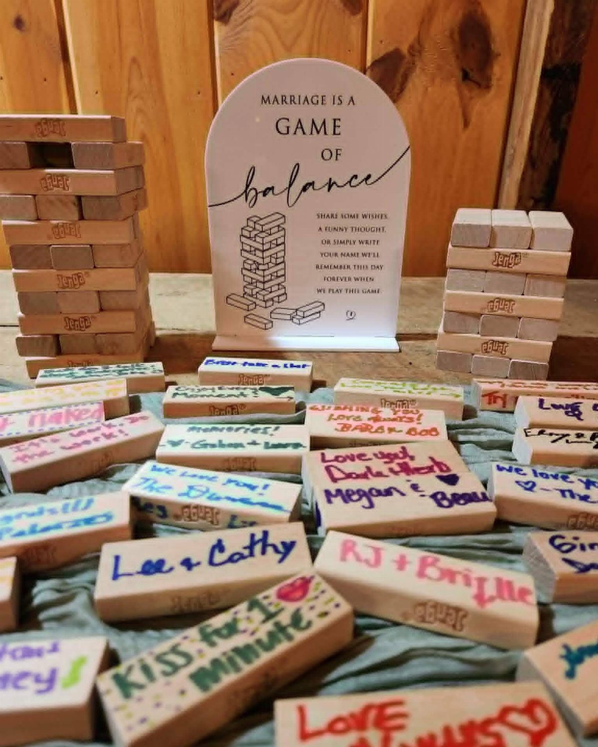 Wooden Jenga blocks signed with colorful messages next to a marriage balance sign.