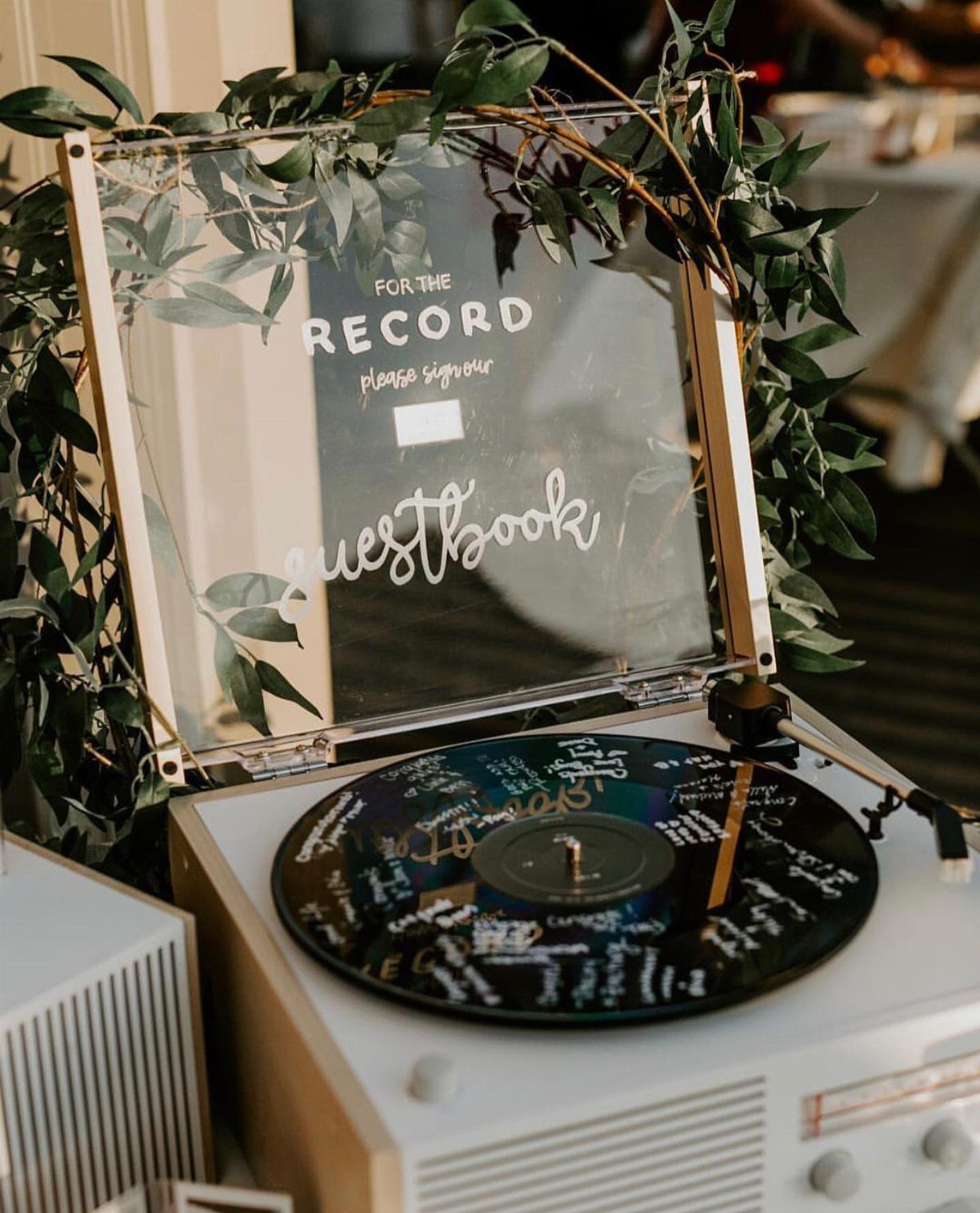Signed black vinyl record on a record player with a guestbook acrylic sign.