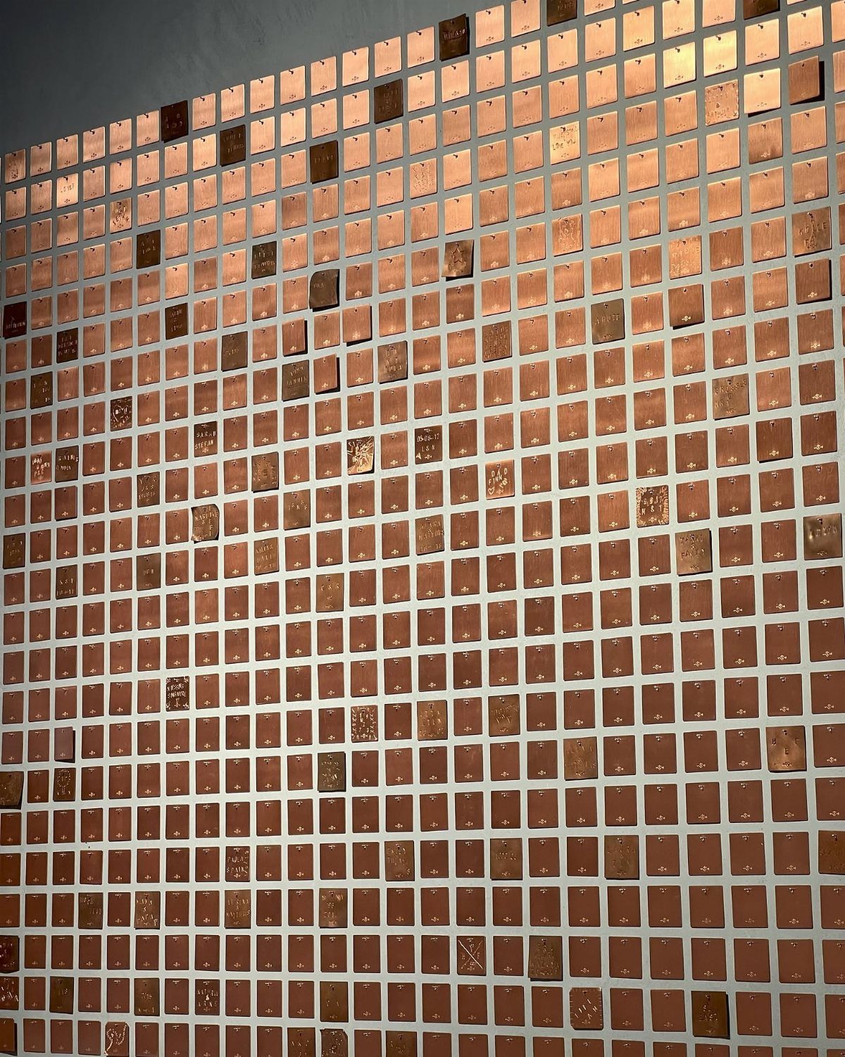 Grid of small copper plates mounted on a wall as artistic installation