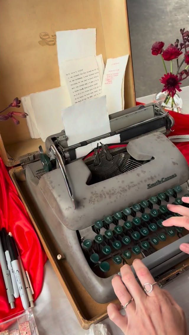 Hands typing on a vintage typewriter with typed messages in a carrying case