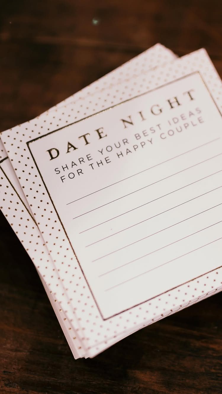 Date night suggestion cards with dotted borders on a dark wooden table.