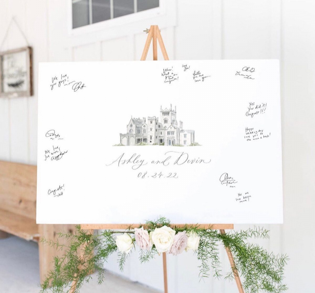 White canvas guest book on an easel with a venue sketch and signatures.