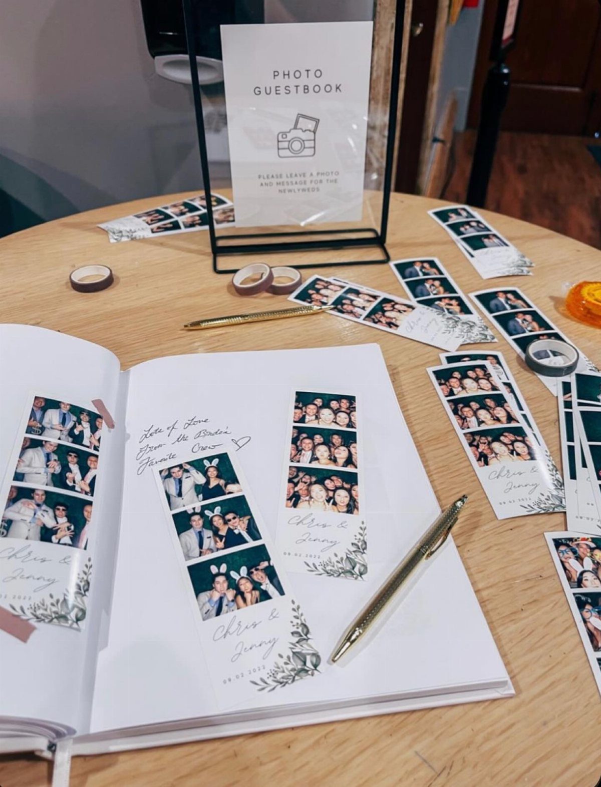 Open guest book with photo booth strips and messages on a wooden table.