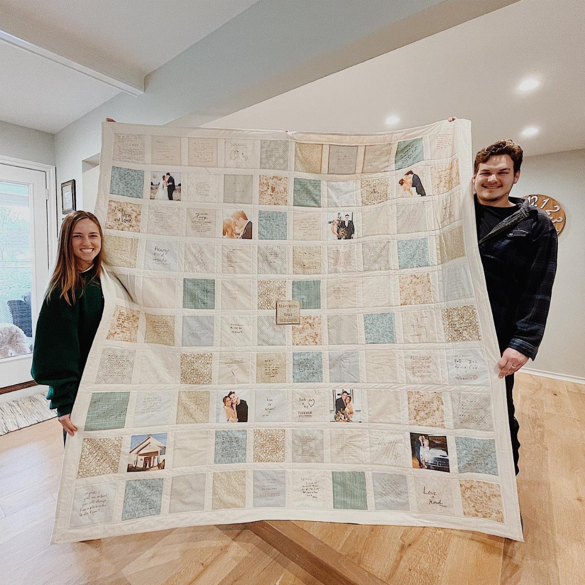 Couple holding a finished quilt guest book with fabric squares, photos, and messages.