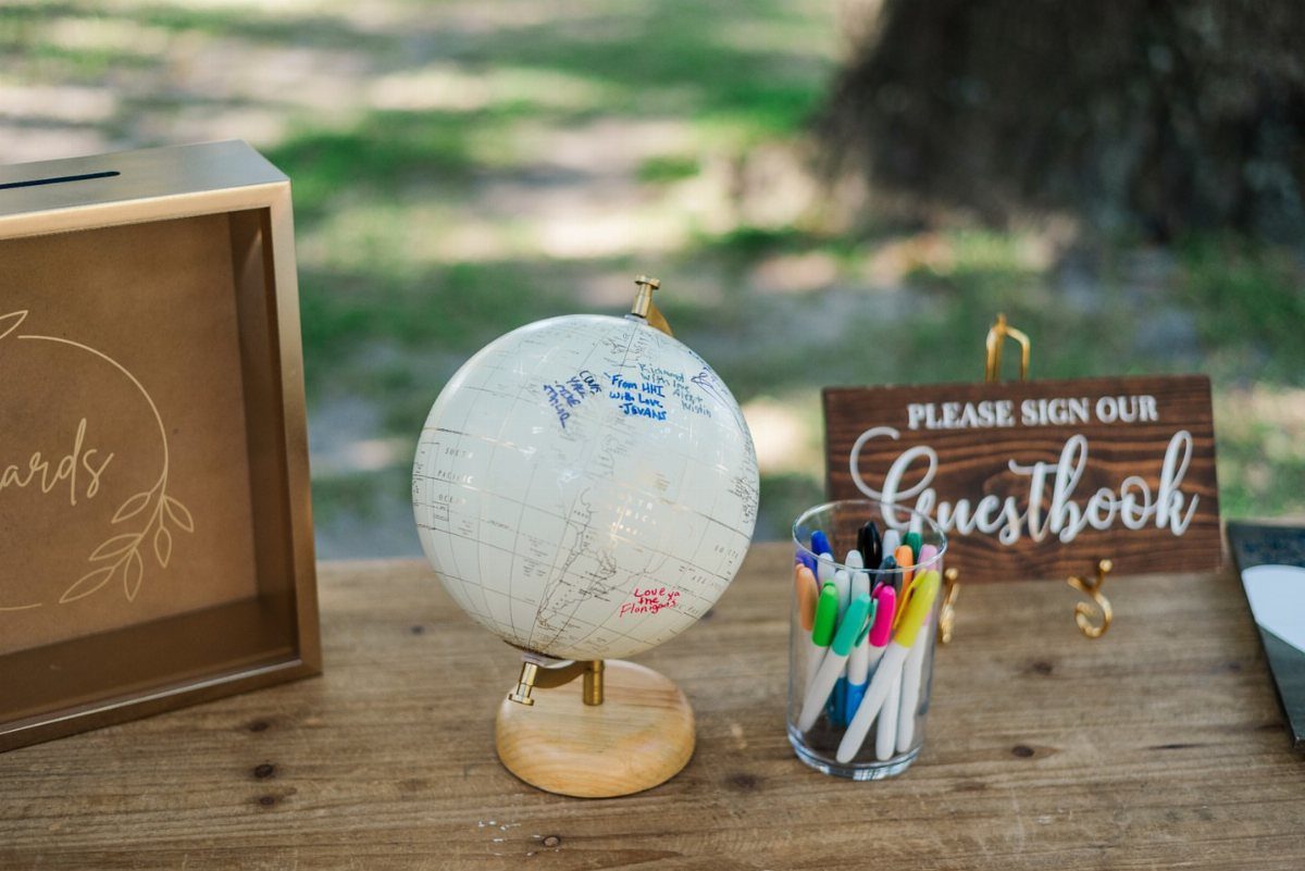 White globe guest book with colorful markers and a wooden sign on a table