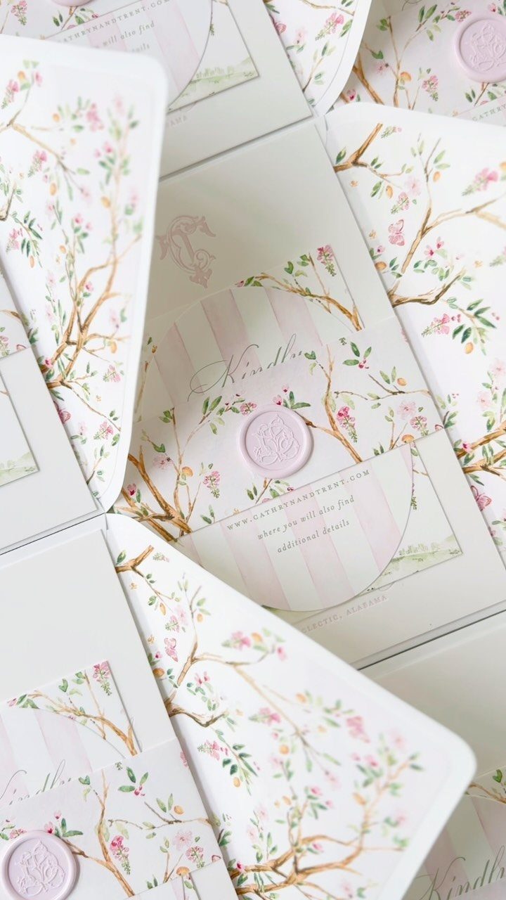 Hand painted wedding invitations with pink floral branches and purple wax seals.
