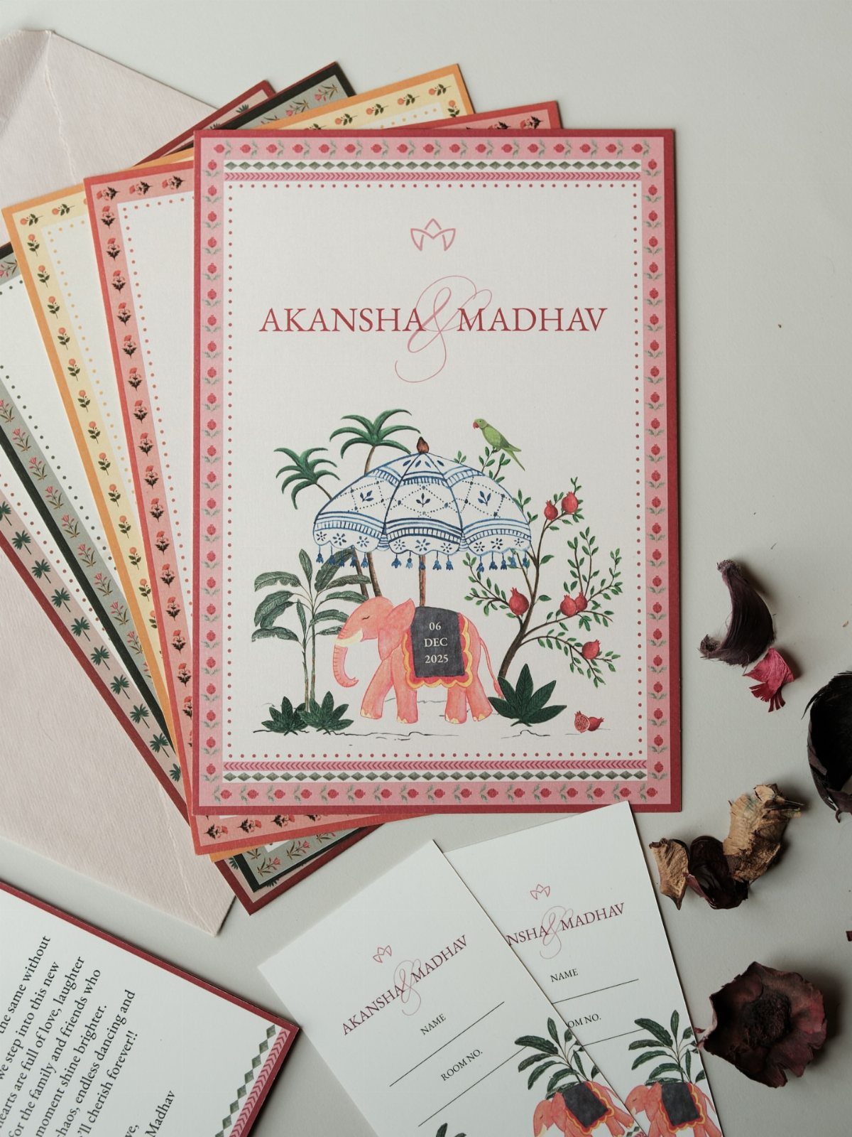 Illustrated wedding invitations featuring an elephant and tropical plants on white paper.