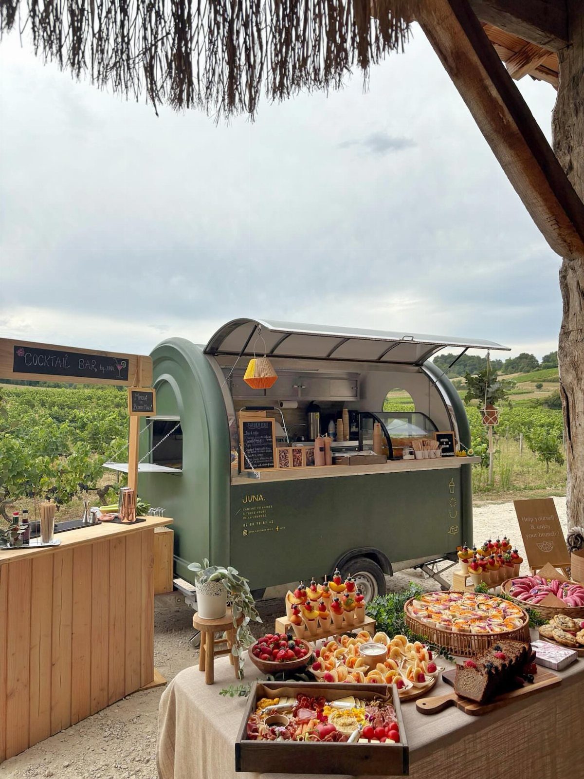 Green vintage food truck with a buffet of appetizers and desserts outdoors.