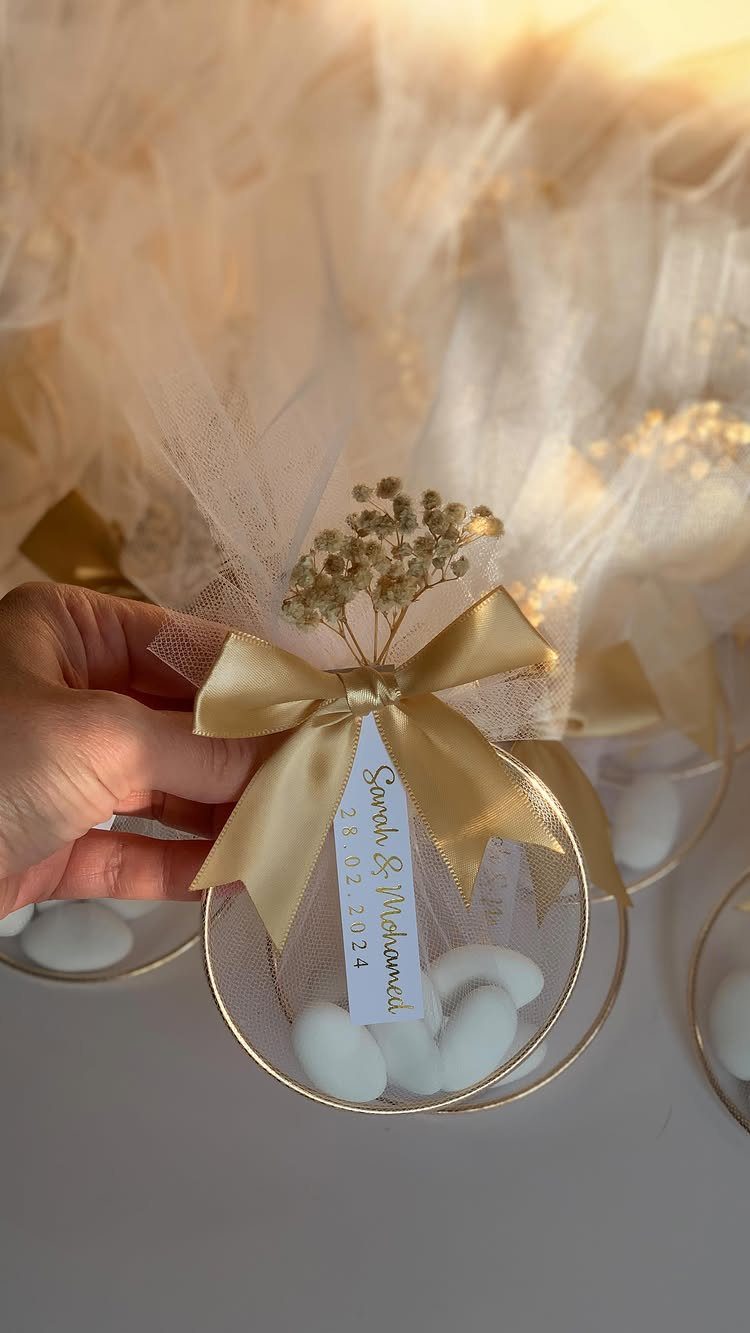 Wedding favor with white almond candies in a gold dish with a bow.