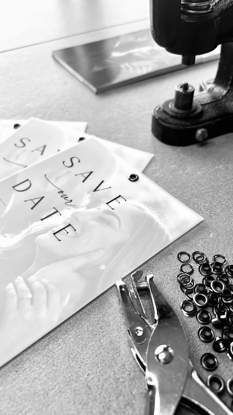 Save-the-date cards with a couple's photo next to metal grommets and tools.