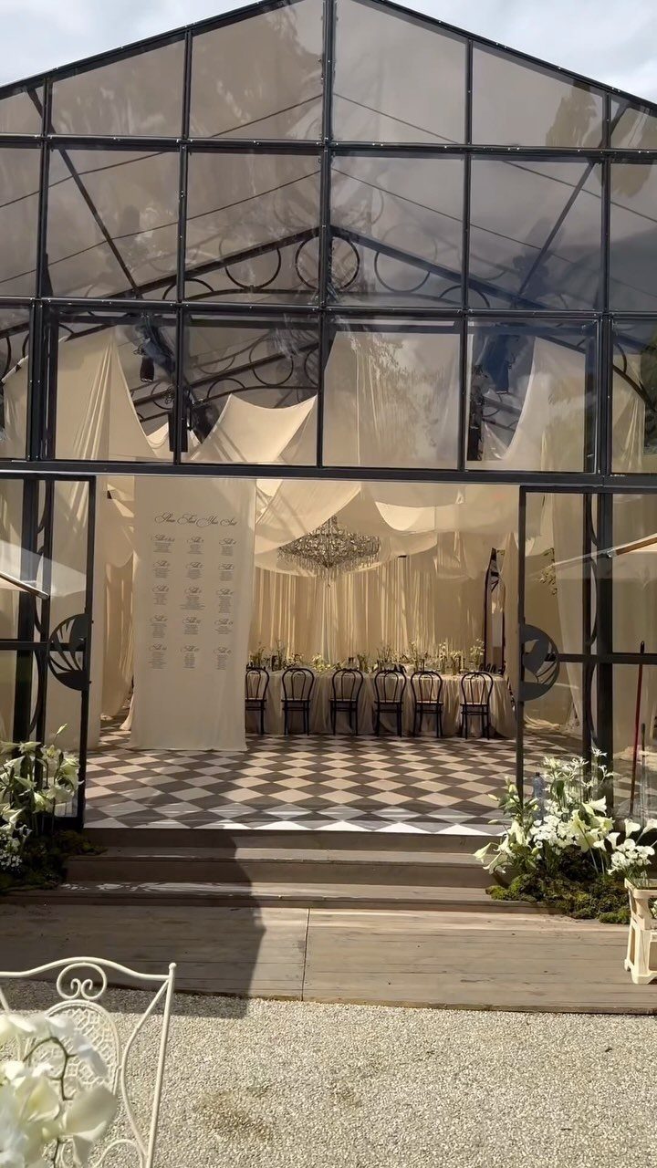 Glass greenhouse wedding venue with a decorated dining table and checkered floor