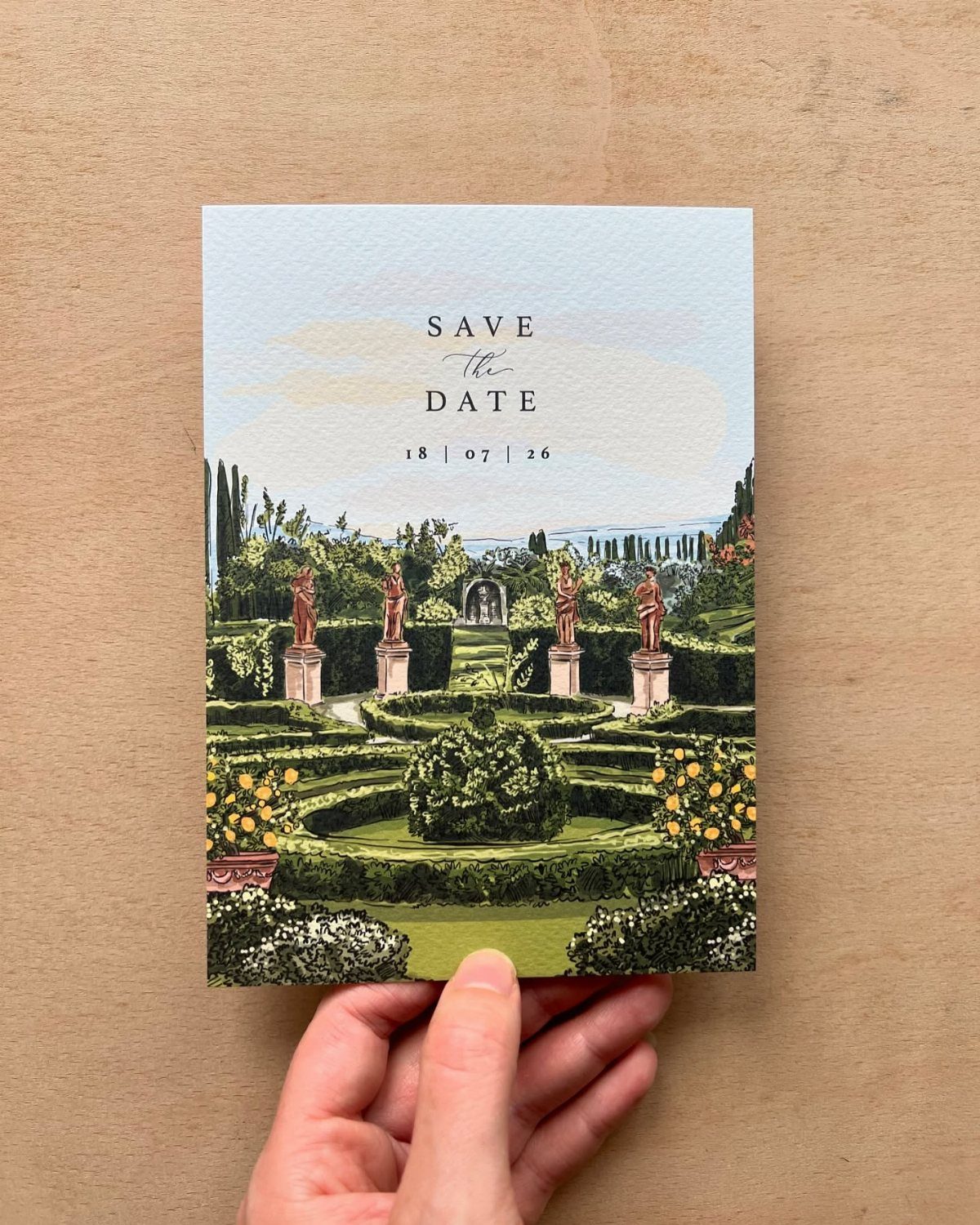 Illustrated save the date card featuring a formal garden held by a hand.