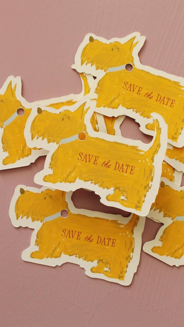 Yellow dog shaped save the date cards scattered on a pink surface.