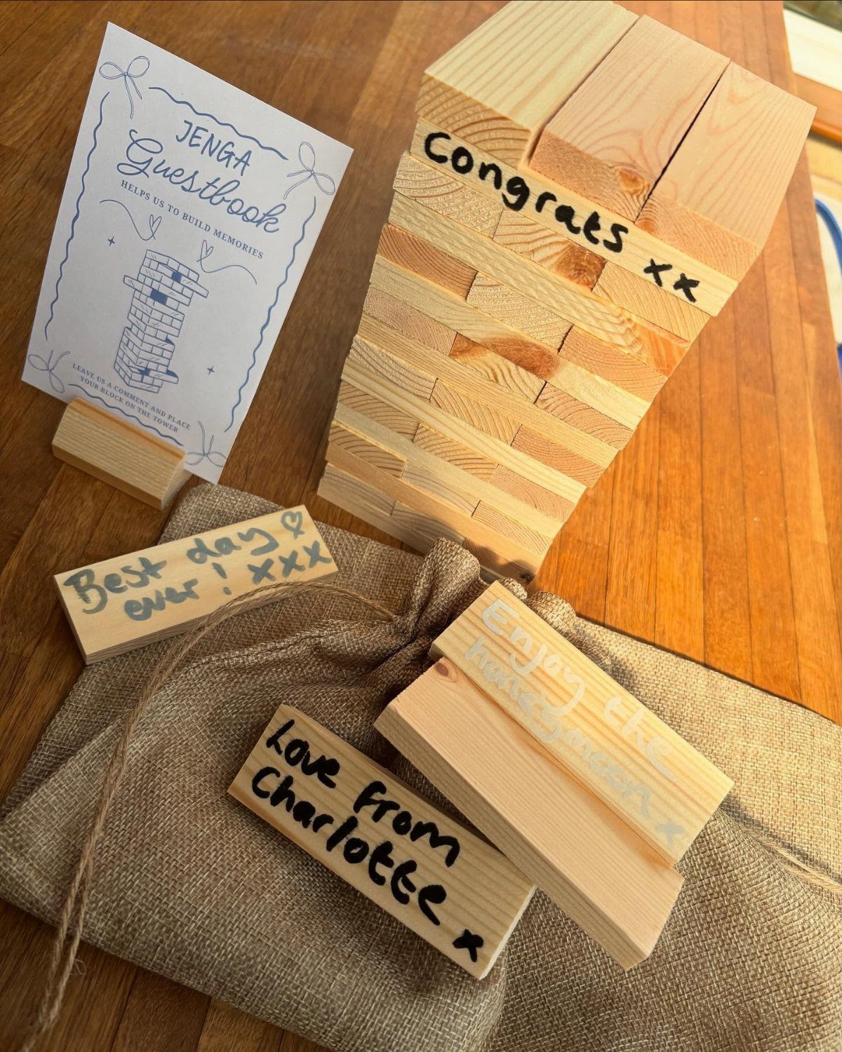 Wooden Jenga blocks with handwritten wedding guest messages and a guestbook sign.