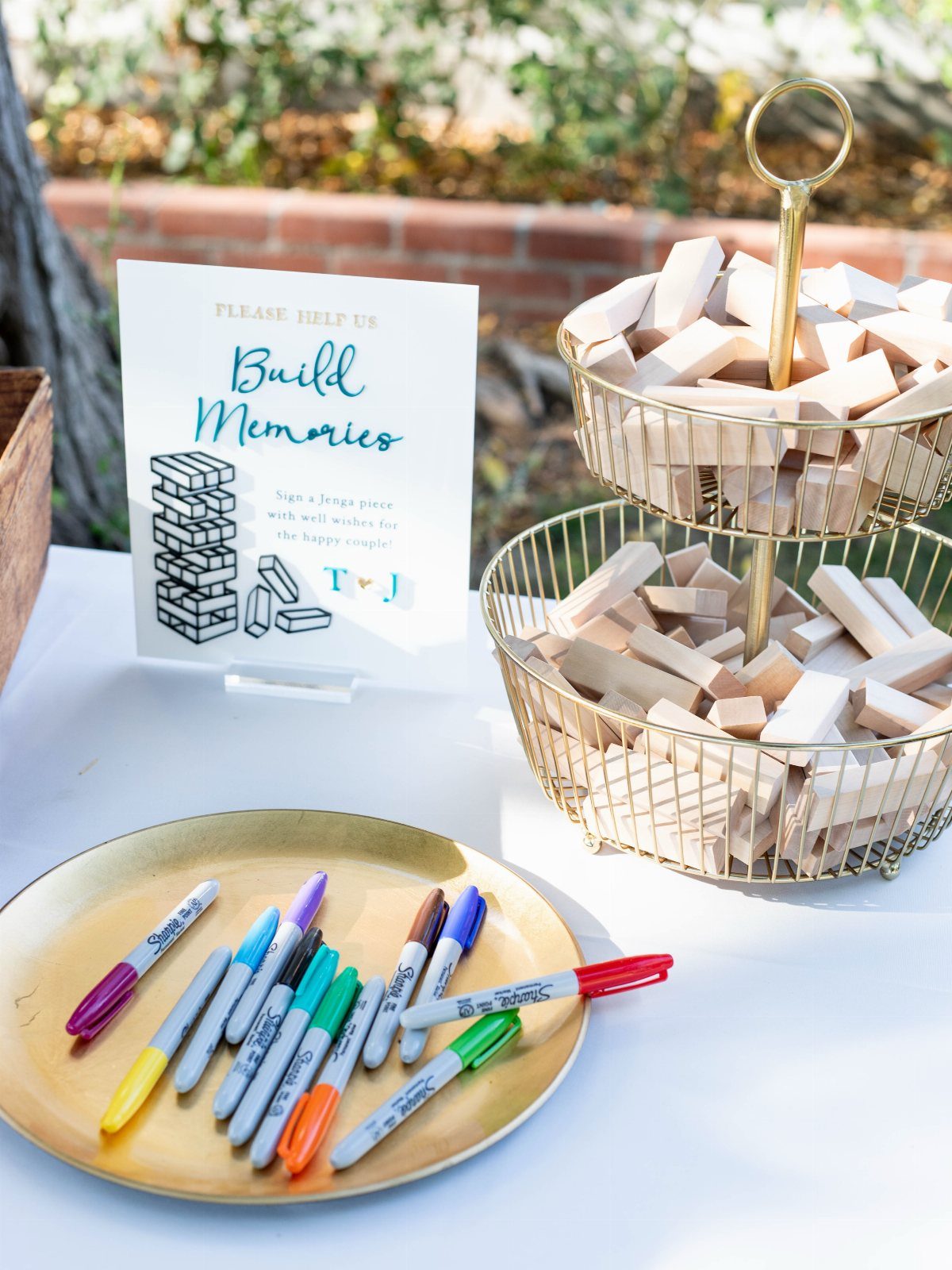 Wooden Jenga blocks in gold baskets with markers and a Build Memories sign.