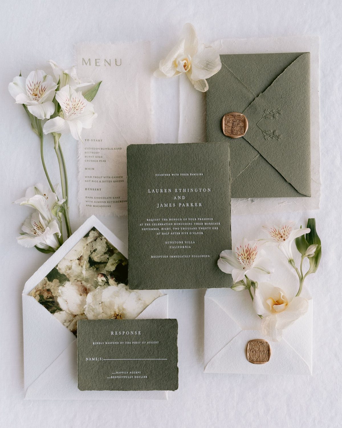 Olive green wedding invitation suite with white flowers and gold wax seals.