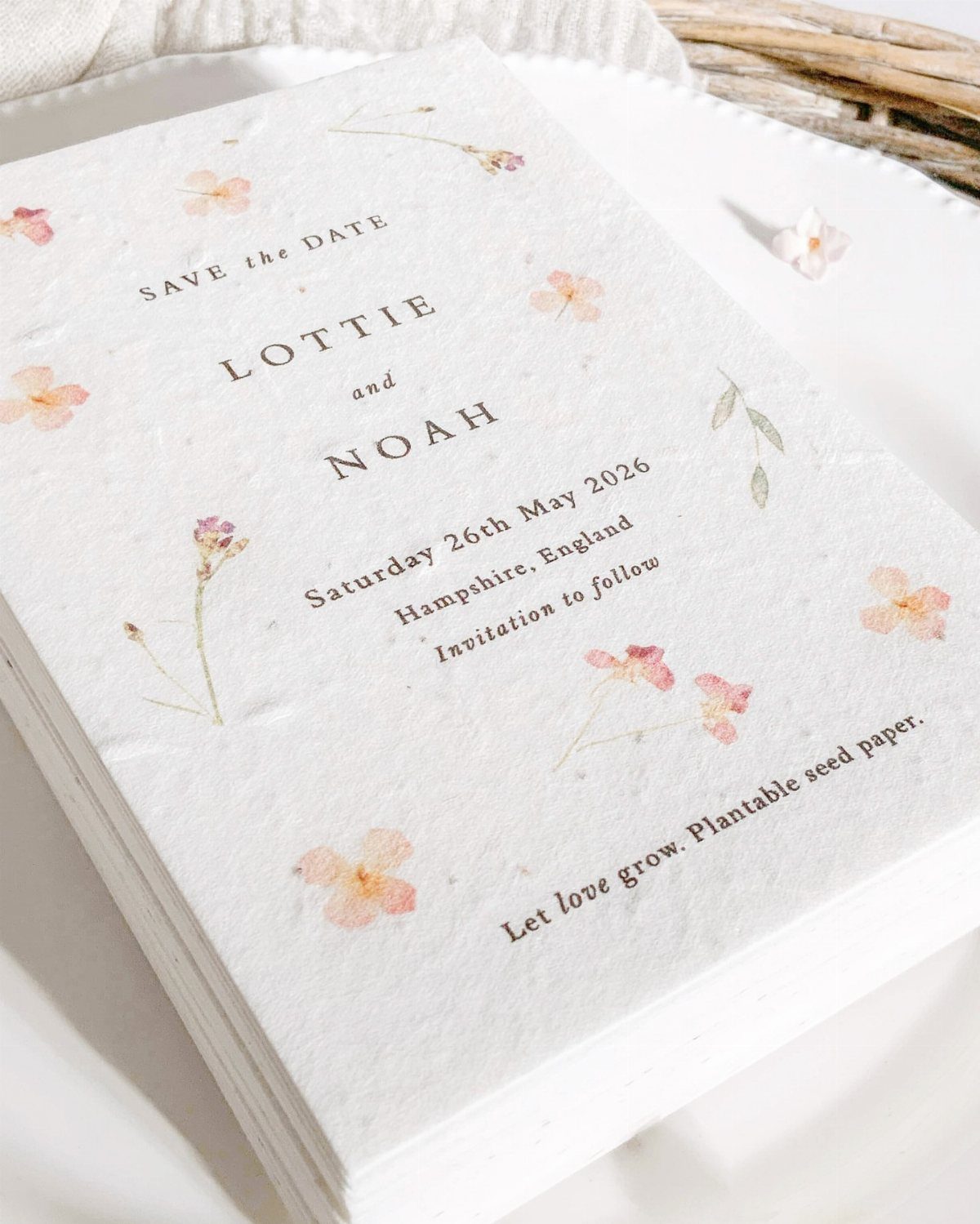 Seed paper save the date cards with embedded dried flowers and black serif text.