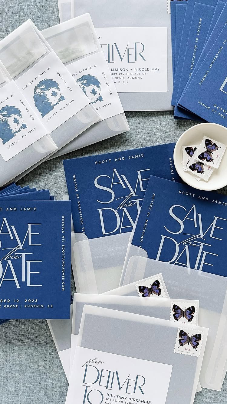 Navy blue save the date cards with translucent vellum overlays and butterfly stickers.