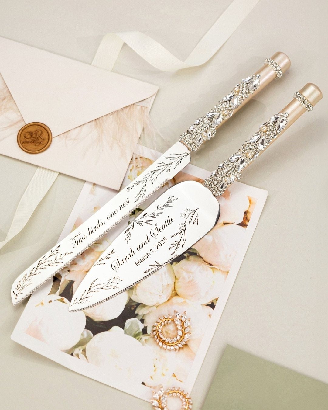 Silver cake knife and server with crystal handles resting on floral stationery.