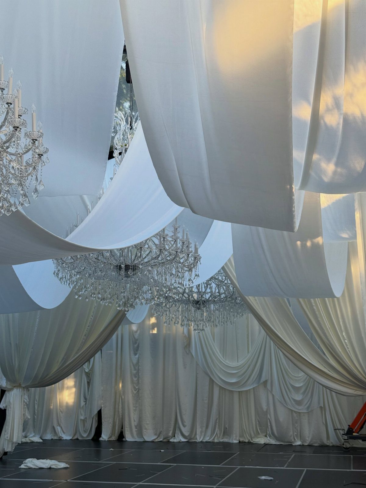 White fabric draping and crystal chandeliers in a wedding venue setting.