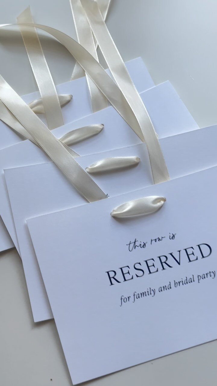 Reserved seat cards with white satin ribbons for a wedding bridal party.
