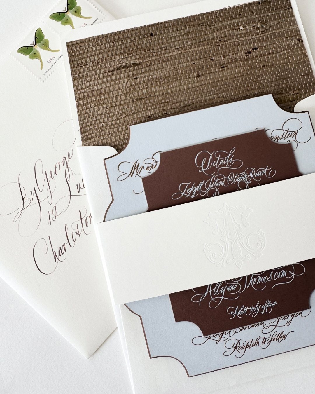 Wedding invitations with burlap texture, blue and white cardstock, and elegant cursive calligraphy.