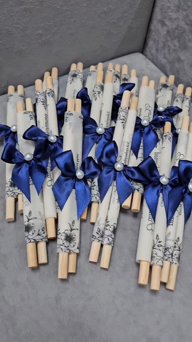 Scroll wedding invitations rolled on wooden dowels with blue satin bows and pearls.