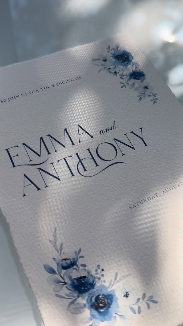 Wedding invitation with blue watercolor flowers and elegant dark blue text on white paper.