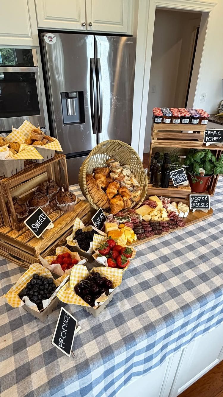 Food spread with berries, pastries, and charcuterie on a blue checkered tablecloth.