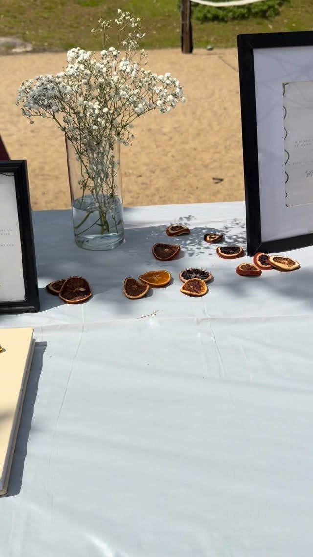 Baby's breath flowers in a vase and dried orange slices on a white tablecloth