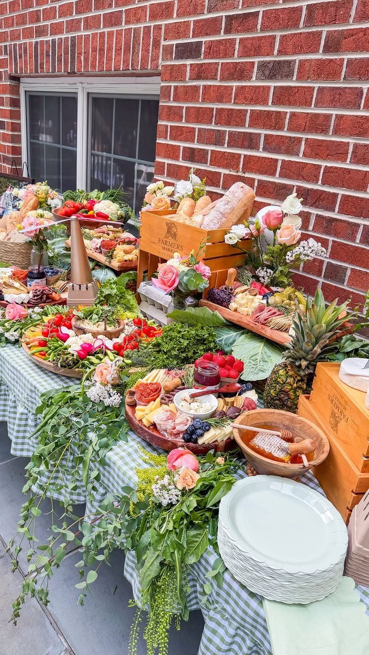 Charcuterie boards and fresh produce arranged on a striped tablecloth against brick wall