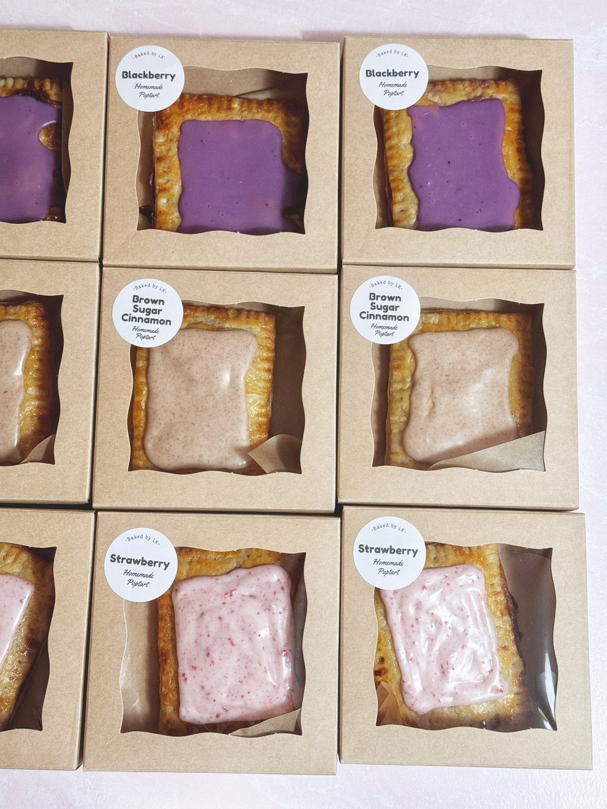 Pastry tarts with strawberry, blackberry, and cinnamon toppings in brown cardboard boxes.