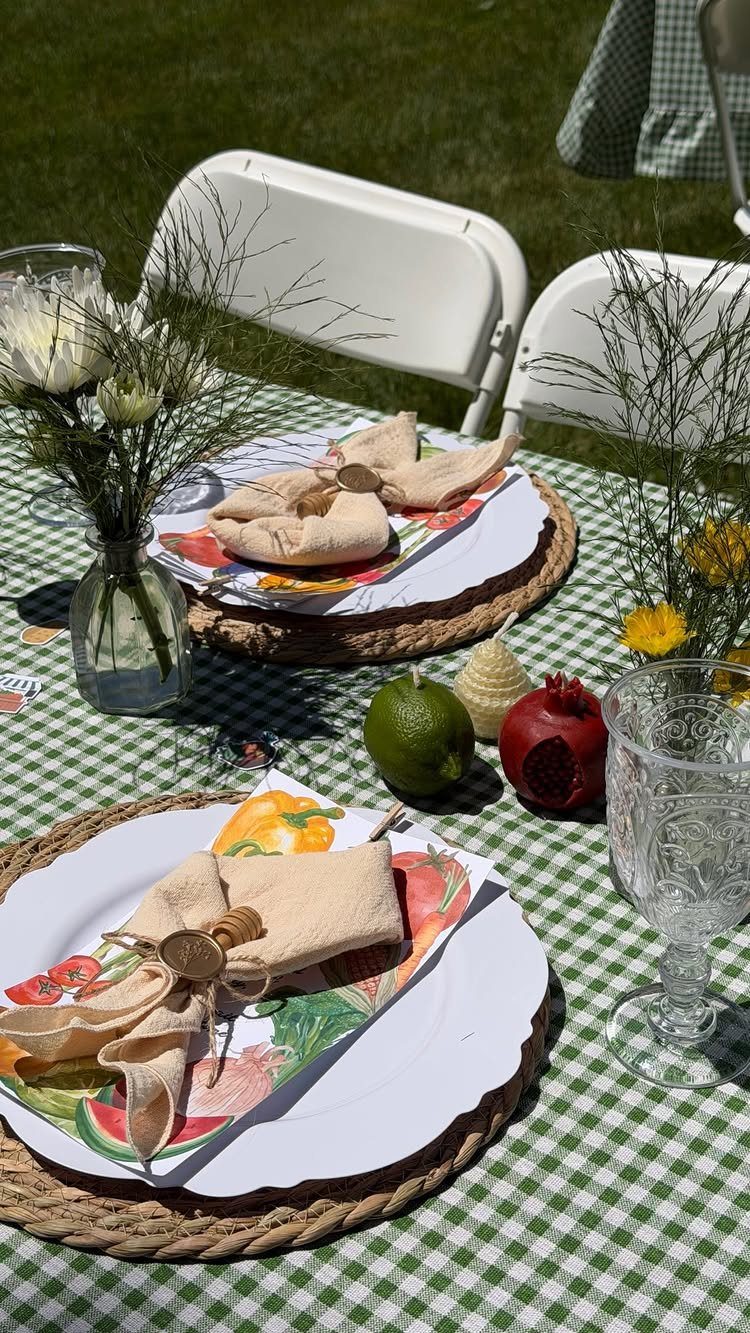 Outdoor table setting with checkered cloth, woven chargers, and fresh fruit accents.