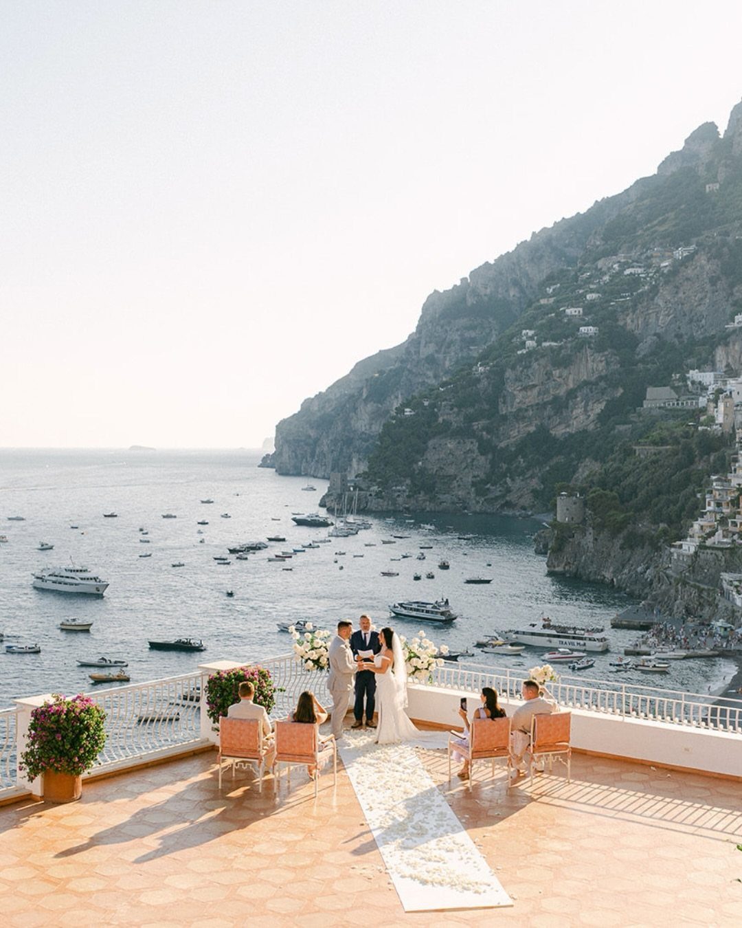 Wedding ceremony on a scenic terrace overlooking a Mediterranean coastal town and sea.