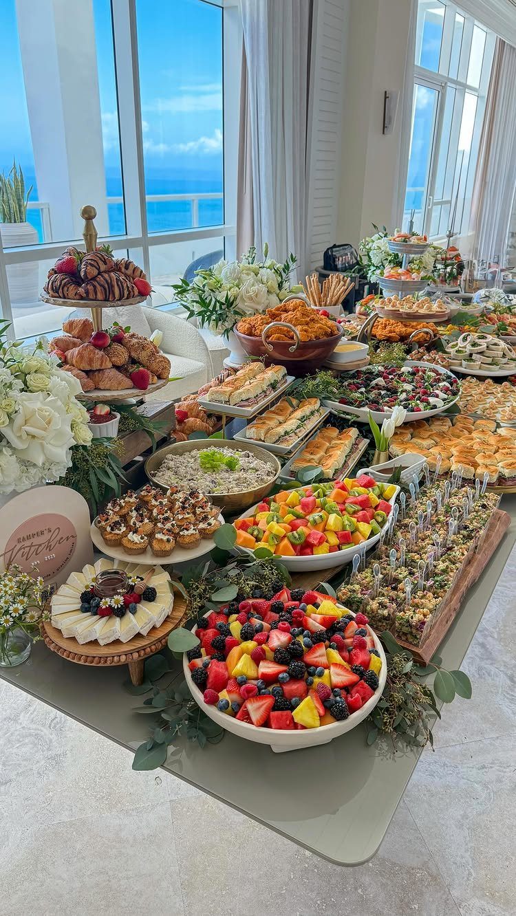 Buffet spread with fruit, pastries, and savory dishes overlooking a blue ocean view.