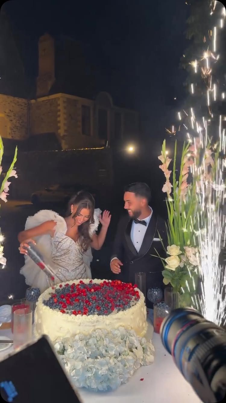 Bride and groom cutting a berry-topped wedding cake with sparklers in the background