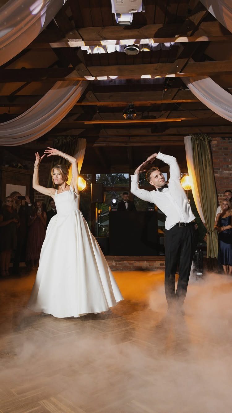 Bride and groom dancing their first dance surrounded by fog in a ballroom.