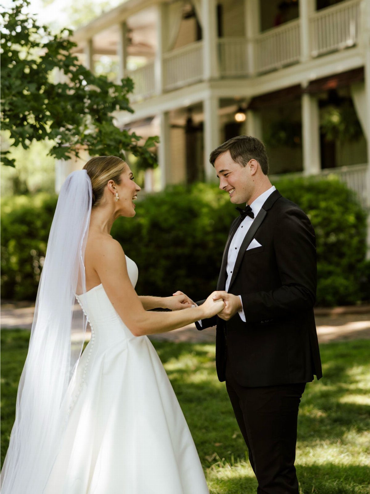 Bride and groom holding hands and smiling during their first look portraits outdoors.