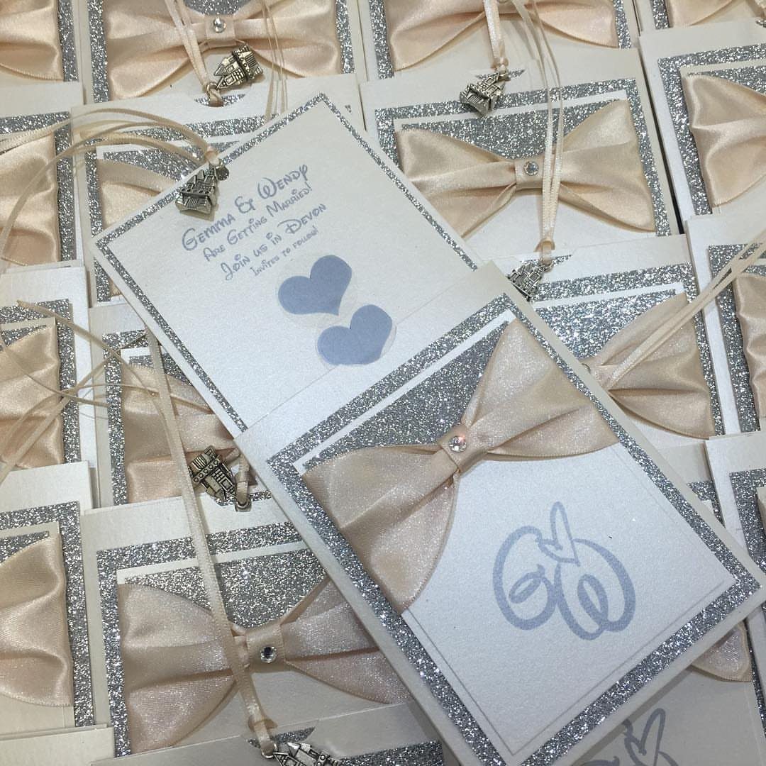 White wedding announcement cards with silver glitter borders and champagne satin bows.