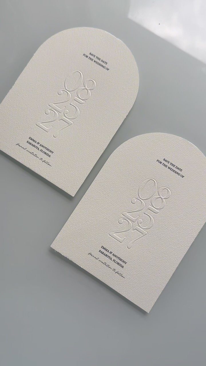 Two arched off-white save-the-date cards with embossed designs and minimal black text.