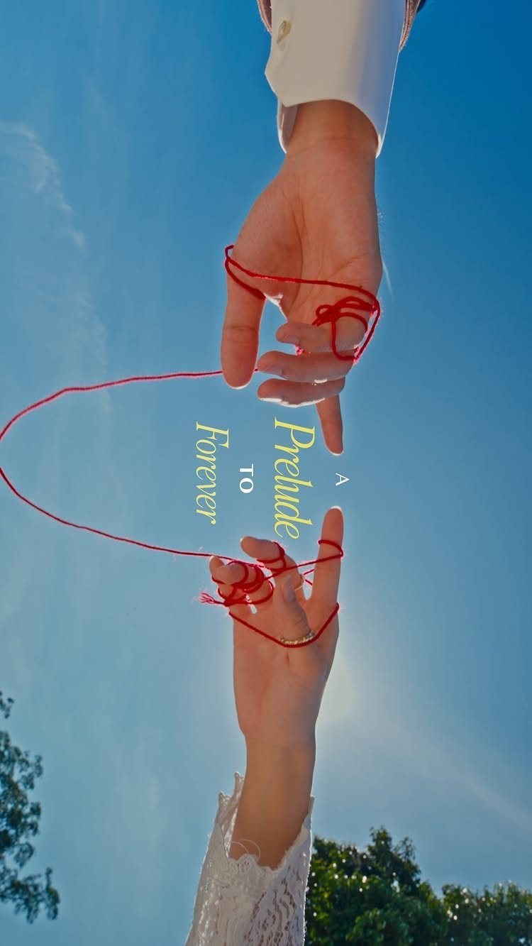 Hands holding a clear acrylic save the date card with a red string.